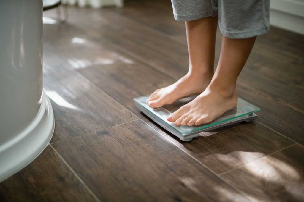 woman stepping on scale concerned about body image and eating disorders